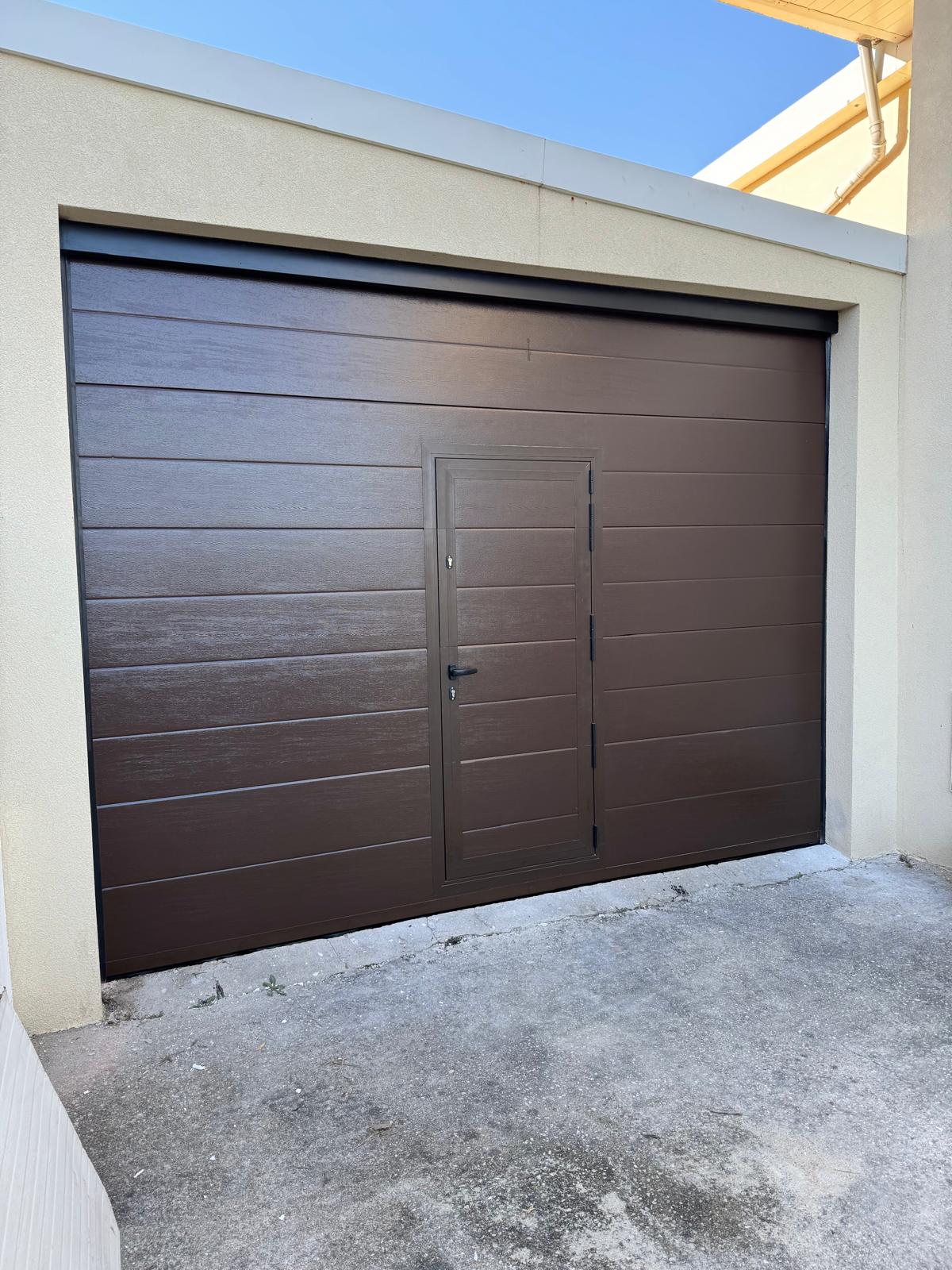 Porta seccionada de garagem castanha com porta pedonal integrada